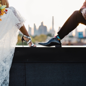 Младоженци седят на ръба с изглед към града – романтична сватбена фотосесия